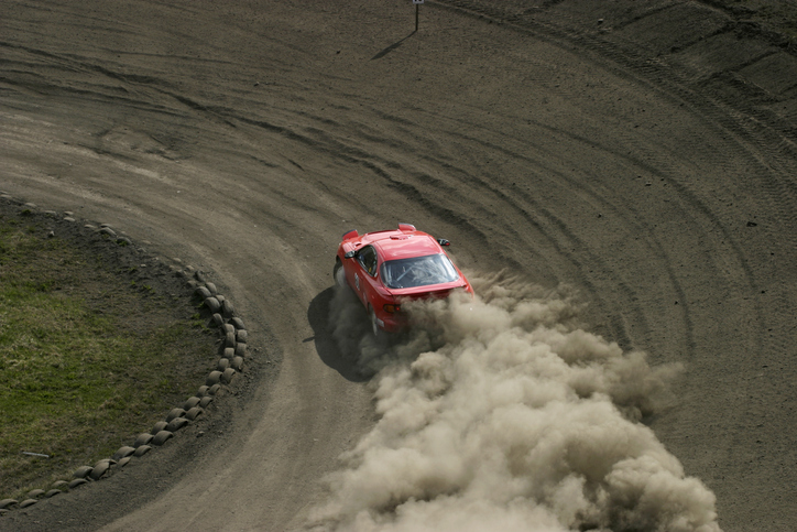 red race car driving on a dirt track